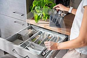 A woman housewife hands tidying up cutlery after dishwasher machine. Woman neatly assembling fork, spoon, knife