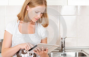 Woman housewife in the kitchen with an blank tablet computer