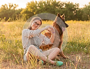 Woman hug her dog German Shepherd in summer park on sunset