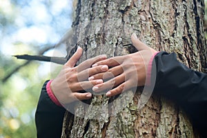 Woman hugging a big tree in a park.