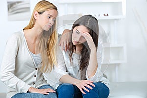 Woman hugging depressed friend at home