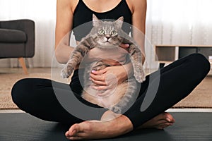 Woman hugging her cat while practicing yoga at home, closeup