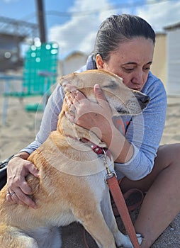 Woman hugging her dog on the beach