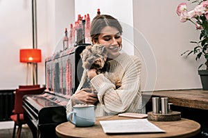 Woman hugging her dog while sitting in a cafe