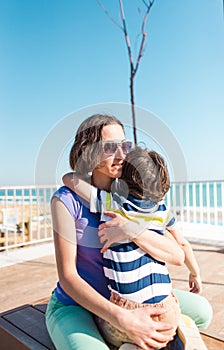 Woman is hugging her son on the beach