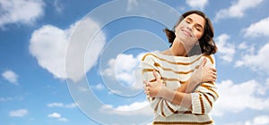 Woman hugging herself over heart shaped cloud