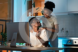Woman hugging husband from behind while he working on computer remotely from home late at night