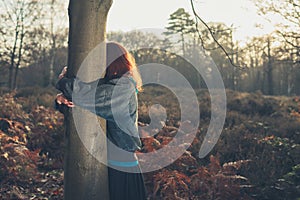 Woman hugging tree at sunset