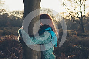 Woman hugging tree at sunset