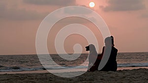 Woman hugs her dog at sunset