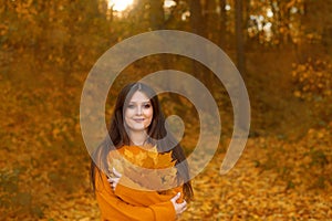 woman hugs self, care about mental health, holding leaves bouquet and walking in autumn park