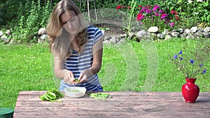 Woman hulled fresh peas in plate sitting at table in garden. 4K