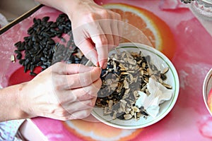 Woman hulls sunflower seeds. Roasted sunflower seeds and husks on a plate