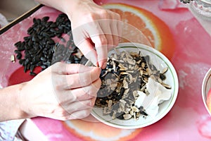 Woman hulls sunflower seeds. Roasted sunflower seeds and husks on a plate