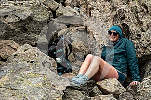 Woman Hunkers Down Behind Large Boulders From Cold Wind