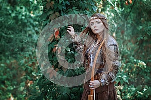 Woman hunter with a bow in hand in the forest. Amazon