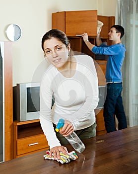 Woman with husband cleaning wooden furiture