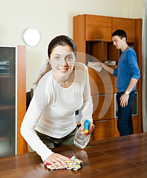 Woman with husband cleaning wooden furiture