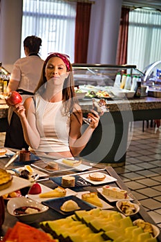 Woman with an ice cream cup in one hand and an apple in the other with a happy expression