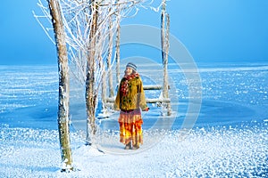 Woman on ice lake in beautiful ethno dress and beautiful frozen trees.