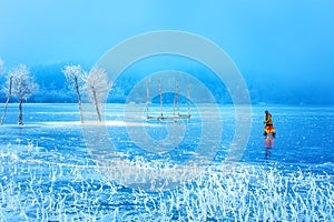 Žena na ľadovom jazere. Zasnežená krajina a zasnežené stromy a ľadové jazero.