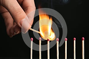 Woman igniting line of matches on black background. Space for text