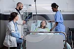 Woman with illness connected to iv drip line and monitor showing vitals recieving medical care
