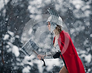 Woman in image of Germanic-Scandinavian God of thunder and storm goes with hammer in her hand. Cosplay.