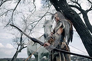 Woman in image of warrior amazon shoots a bow near her horse