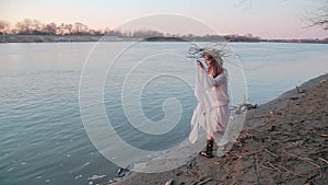 Woman in the image of witch and old Slavic costume runs on Bank of river near forest