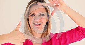 Woman imitates camera with fingers creating fun snapshot