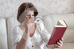 Woman with impaired vision reading a book through two glasses