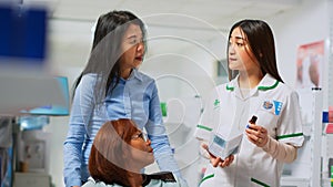 Woman with impairment and caretaker talking to pharmacist