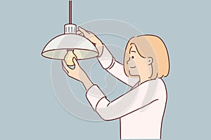 Woman independently changes burned-out light bulb in order to achieve high-quality lighting in house