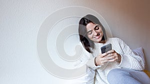 Woman indoor portrait. Young beautiful using her mobile phone. woman in warm knitted clothes at home. fashion. Autumn, winter