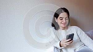 Woman indoor portrait. Young beautiful using her mobile phone. woman in warm knitted clothes at home. fashion. Autumn, winter