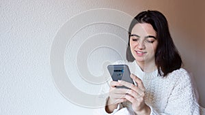 Woman indoor portrait. Young beautiful using her mobile phone. woman in warm knitted clothes at home. fashion. Autumn, winter