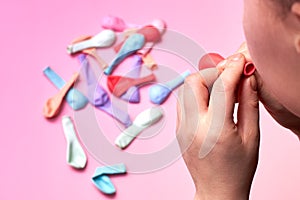 Woman inflates a balloon on a pink background