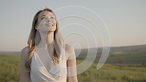 Woman inhales the heady aroma of fresh air and catches the evening rays of the sun