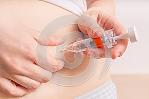 Woman is injecting hormones to belly with syringe.