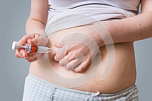 Woman is injecting hormones to belly with syringe. photo