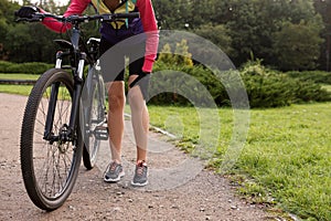 Woman with injured knee and bicycle outdoors, closeup. Space for text