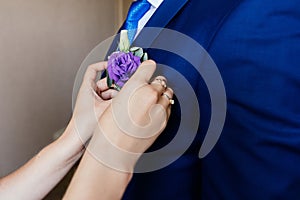 Woman inserting the boutonniere in buttonhole of man