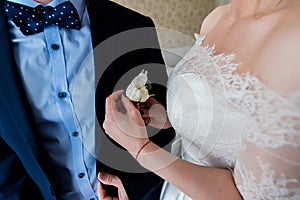 Woman inserting the boutonniere in buttonhole of man in suit