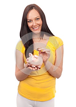 Woman inserting coins in a piggy bank