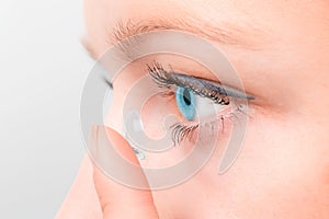 Woman inserting a contact lens in eye.