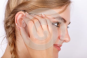 Woman inserting a hearing aid into ear