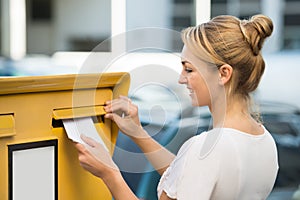 Woman Inserting Letter In Mailbox