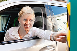 Woman is inserting parking ticket into barrier photo