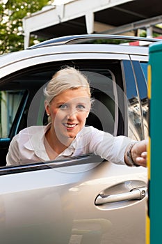 Woman is inserting parking ticket into barrier